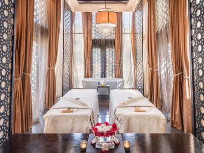 Ein luxuriöses Spa-Zimmer mit zwei Massageliegen und warmen goldenen Vorhängen.