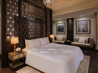 Modern eingerichtetes Hotelzimmer mit großem Bett, dekorativen Paneelen und gemütlicher Beleuchtung.