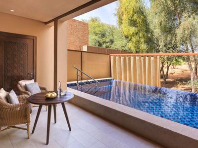 Terrasse mit zwei Stühlen, Tisch und kleinem Pool mit Blick auf Bäume und Natur.