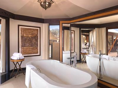 Elegantes Badezimmer mit freistehender Badewanne, großen Spiegeln und natürlichem Licht.