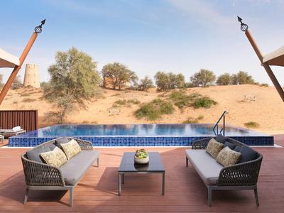 Terrasse mit zwei schwarzen Sofas und einem Pool mit Blick auf eine Wüstenlandschaft.
