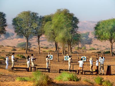 Gruppe von Menschen steht im Freien in einer trockenen, baumreichen Landschaft mit Zielen.