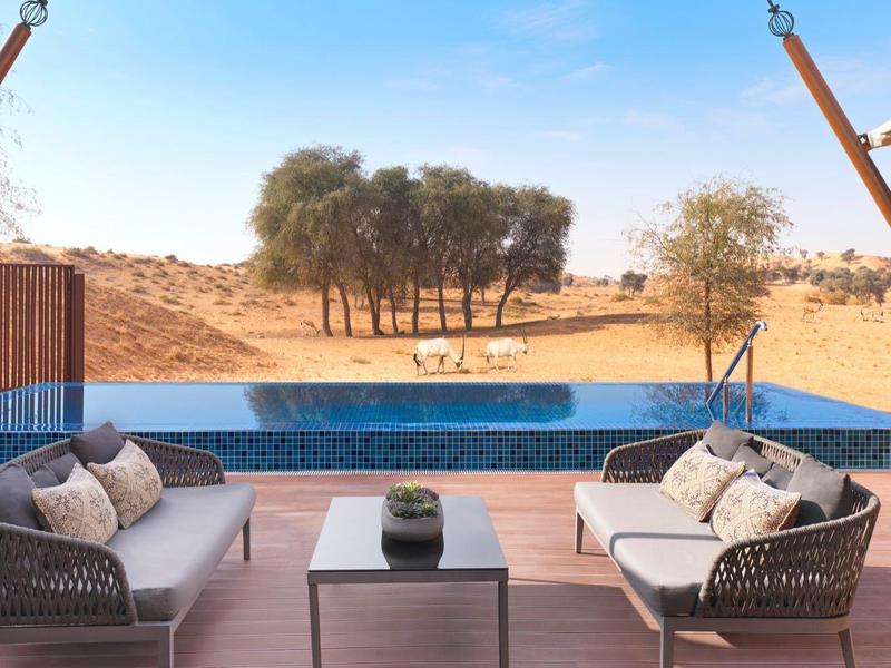 Moderne Terrasse mit zwei Sesseln und Pool mit Blick auf die Wüste.