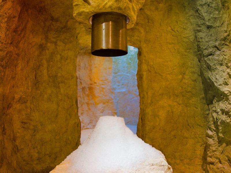 Natürlicher Felsbrunnen mit Wasser, das in eine runde Steinmulde tropft, umgeben von felsiger Wand.