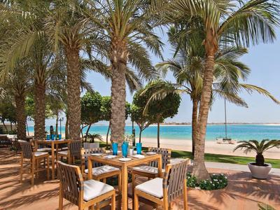 Strefa siedząca na świeżym powietrzu z drewnianymi stołami i krzesłami pod palmami przy plaży