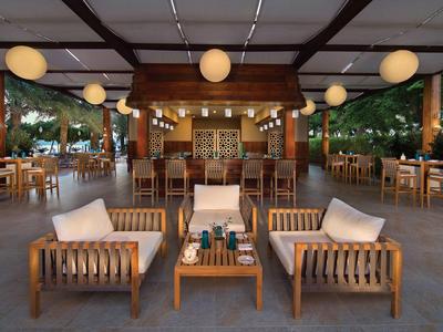 Offener Lounge-Bereich mit Holzmöbeln und runder Beleuchtung in einem Hotel.