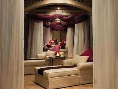 Bequeme Liege mit Kissen und angrenzendem Tisch in einem warm beleuchteten, privaten Bereich mit Vorhängen.