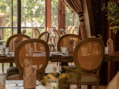 Elegancka restauracja z krzesłami o oparciu w kształcie koła i nakrytymi stołami przy dużych oknach.