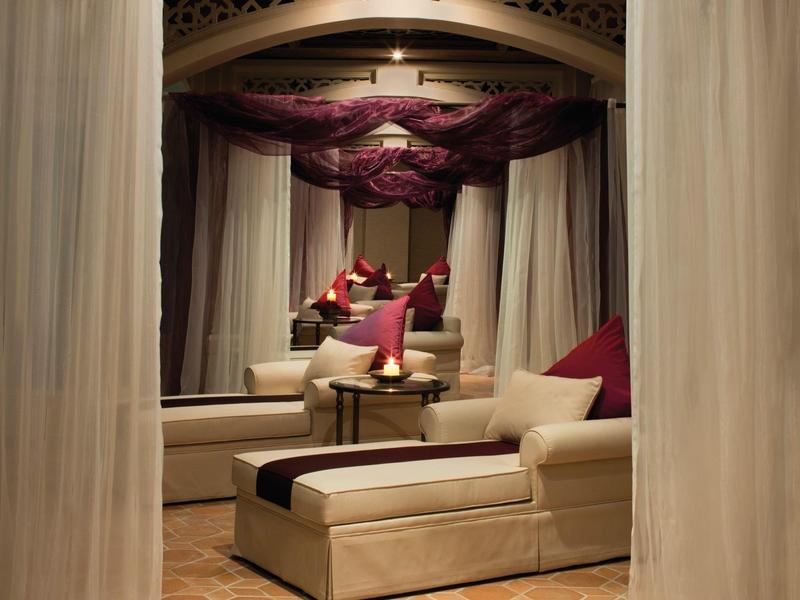 Bequeme Liege mit Kissen und angrenzendem Tisch in einem warm beleuchteten, privaten Bereich mit Vorhängen.