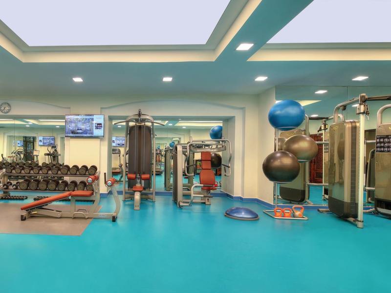 Großer Fitnessraum mit blauer Bodenmatte und verschiedenen Trainingsgeräten.