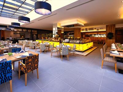 Restaurant moderne et lumineux avec des chaises élégantes et un buffet sous un plafond en verre.