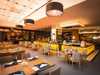 Modern hotel restaurant with warm lighting, wooden furniture, and elegantly set tables.