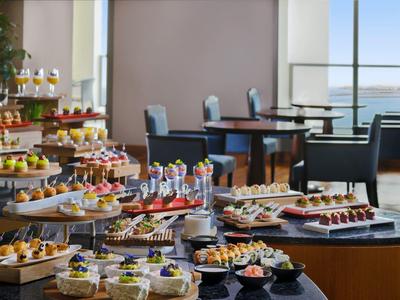 Buffet avec une variété de petits plats artistiquement disposés dans un restaurant élégant avec vue sur la mer.