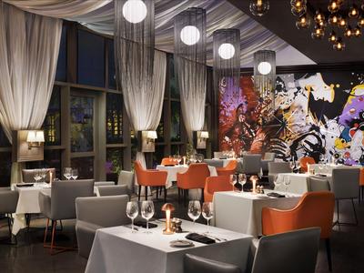 Nowoczesna restauracja z kolorowym muralem, białymi obrusami i eleganckim oświetleniem