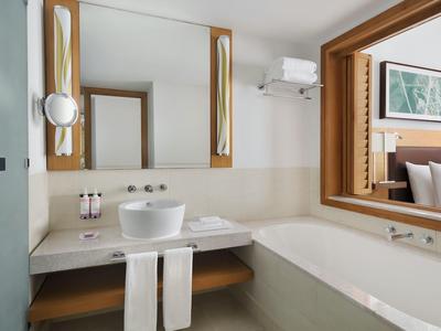 Salle de bain d'hôtel moderne avec baignoire, lavabo, miroir et serviettes.