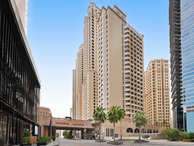 Immeubles modernes et palmiers dans un complexe hôtelier urbain sous un ciel clair.