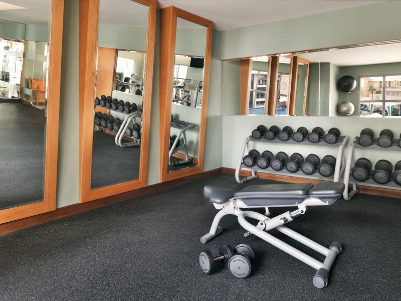Salle de sport moderne avec deux bancs de musculation, haltères et miroirs au mur.