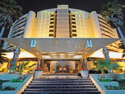 Modern hotel building at night with illuminated entrance and palm trees