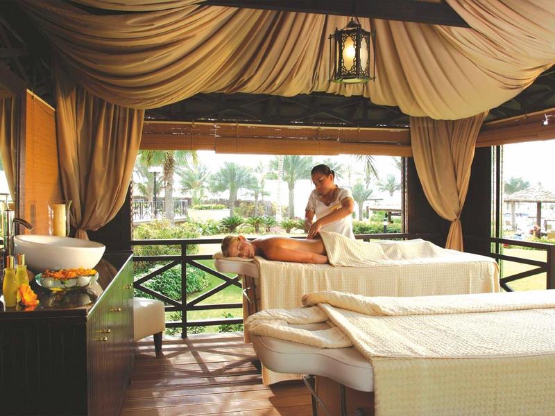 Espace spa ouvert avec tables de massage et thérapeute, ambiance relaxante au bord de l'eau.