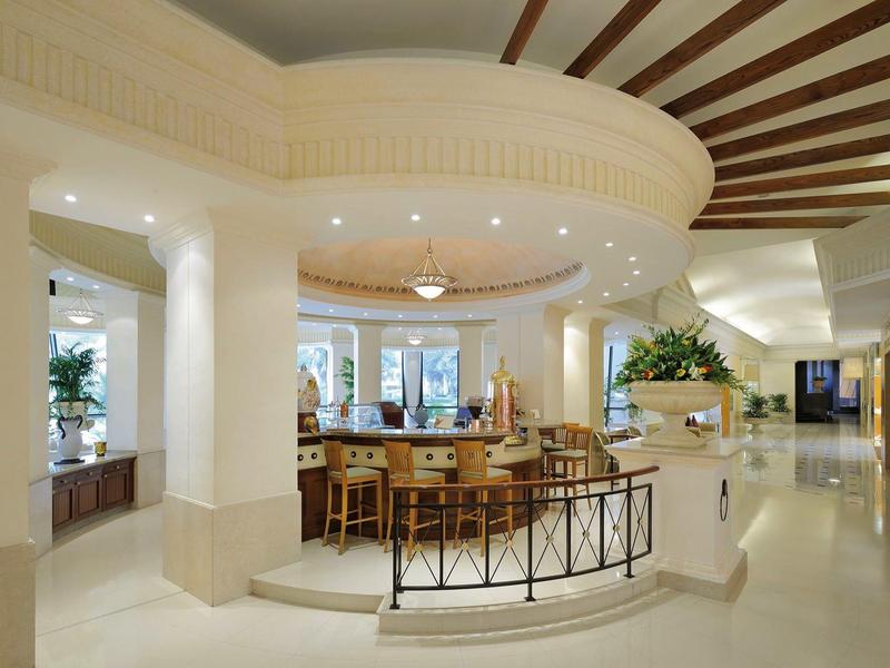 Zone de bar d'hôtel élégante avec intérieur lumineux et comptoir incurvé sous un plafond voûté.