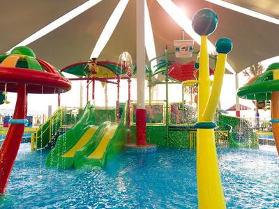 Bunter Wasser-Spielplatz mit Rutschen und Spritzdüsen unter einem großen Sonnendach.