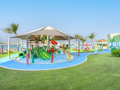 Bunter Kinderspielplatz mit Rutschen und Klettern unter Pavillons am Hotelstrand.