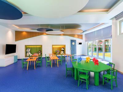 Bunter Spiel- und Essbereich mit kleinen Tischen, Stühlen und moderner Dekoration in einem Hotel.