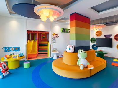 Heller, bunter Spielbereich mit weichen Sitzgelegenheiten und Wanddekoration in einem Hotel.
