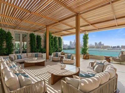 Zadaszony taras z sofami z widokiem na miasto nad wodą.