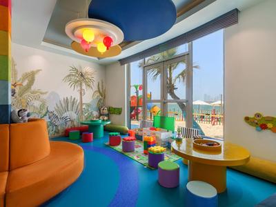 Bunter Kinderspielbereich mit Sitzsäcken, niedrigen Tischen und Wandmalerei in einem Hotel.