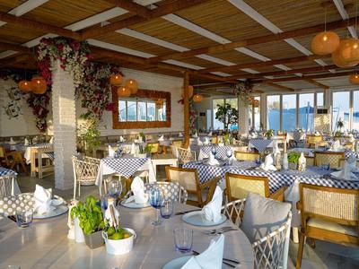 Helles, einladendes Restaurant mit gedeckten Tischen und Holzdecke, Meerblick im Hintergrund.