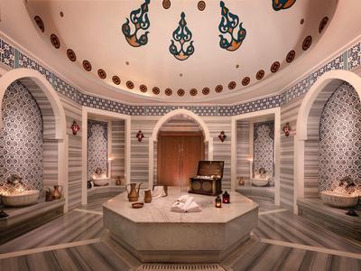 Eleganter Hamam mit sechseckigem Mittelpunkt, dekorierten Wänden und Kuppeldecke.