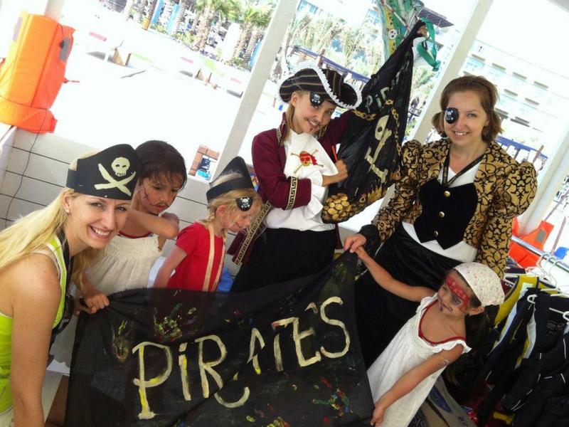 Gruppe von Kindern in Piratenkostümen hält eine schwarze Piratenflagge.