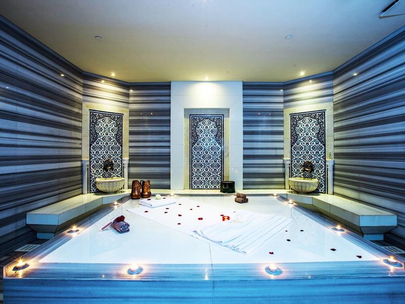 Moderner Spa-Raum mit einem beleuchteten Whirlpool und dekorativen Wänden mit Mosaiken.
