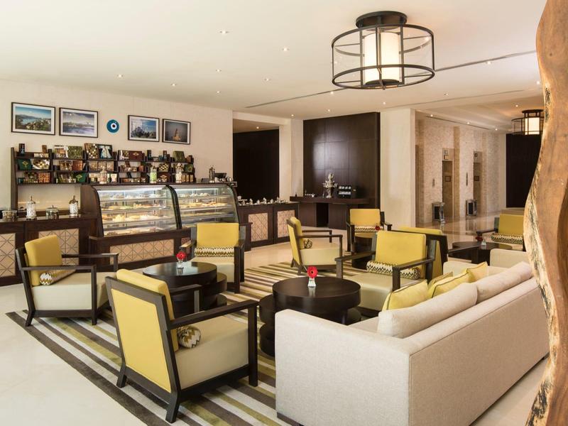 Eleganter Hotel-Loungesalon mit komfortablen Sesseln und Buffet im Hintergrund.