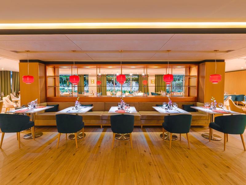 Modernes Restaurant mit Holzboden, blauen Sesseln und eingedeckten Tischen.