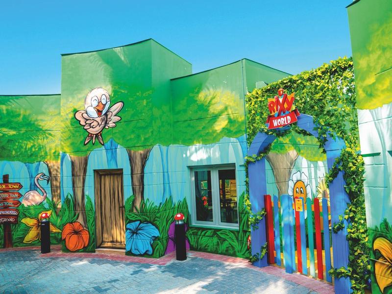 Bunte Hotelwand mit Tier- und Pflanzenmotiven unter klarem blauem Himmel