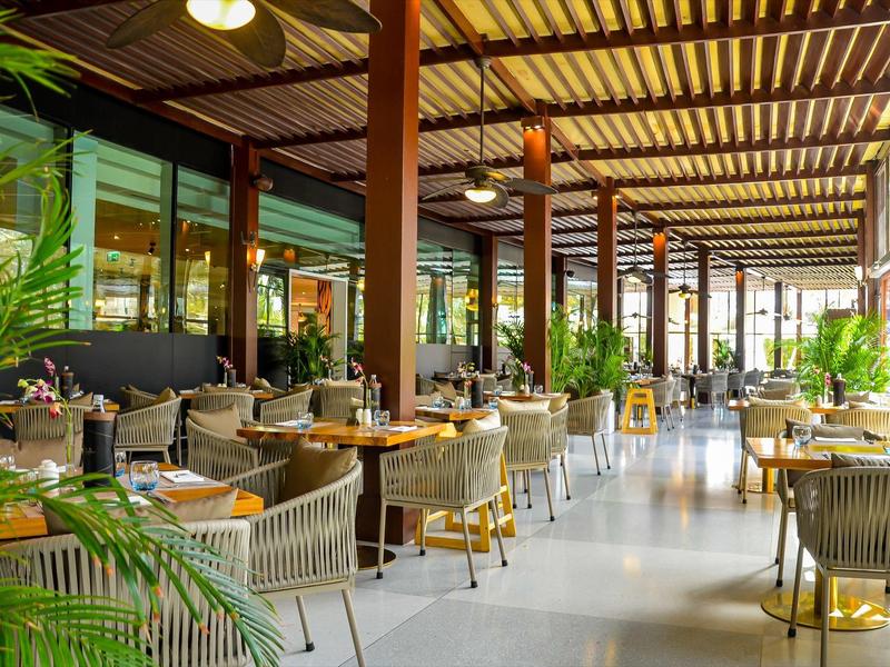 Elegante überdachte Restaurantterrasse mit Holzbalken und modernen Sitzgruppen.