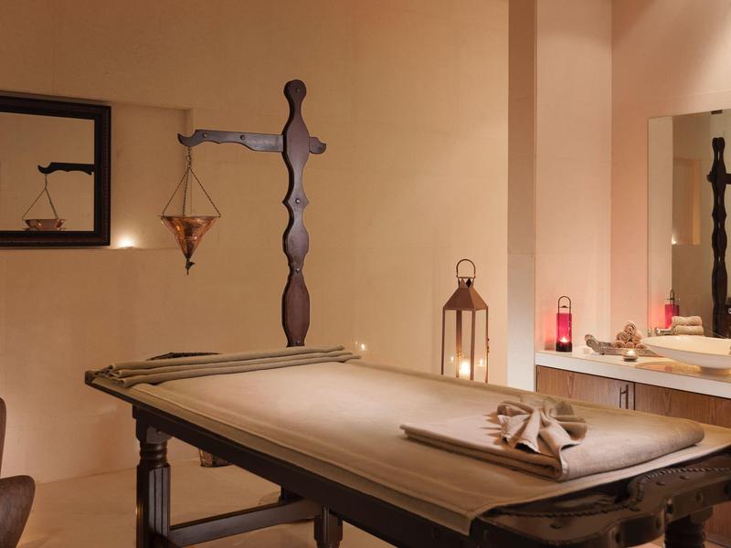 Ein rustikaler Wellnessraum mit Massagetisch, Kerzen und entspannender Atmosphäre.