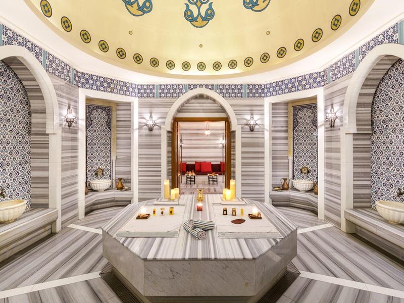 Eleganter türkischer Hamam mit Marmor, bunter Kachelwand und sanfter Beleuchtung