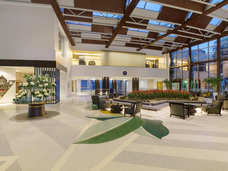 Große Hotellobby mit hohen Decken, modernen Möbeln und viel natürlichem Licht durch Glaswände.