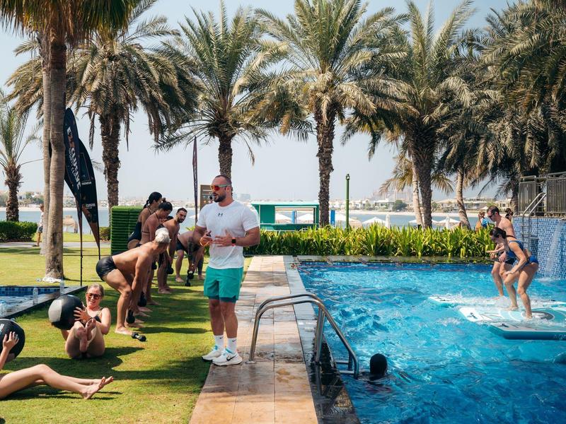 Männer machen Fotos von Frauen am Pool mit Palmen im Hintergrund in einem Resort.