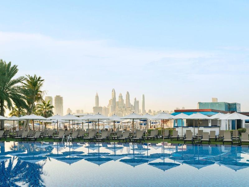 Hotelpool mit Liegestühlen und Blick auf die Skyline bei klarem Himmel