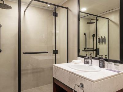 Modern bathroom with shower, mirror, and sink in neutral tones.