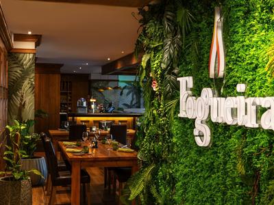 Ristorante accogliente con decorazioni verdi sulla parete e interno in legno per un'atmosfera rilassata.