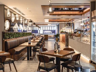 Modern hotel bar with cozy seating, wood and leather furniture, warm lighting, and an open counter.