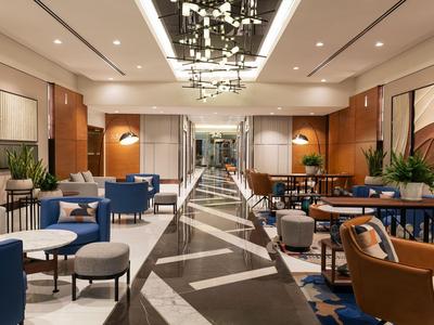 Modern hotel lounge area with blue and brown leather chairs and a wide central aisle.
