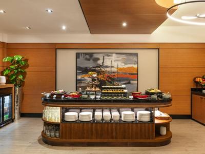 Buffet area with food, drinks, and dishes in a modern room with wooden paneling.