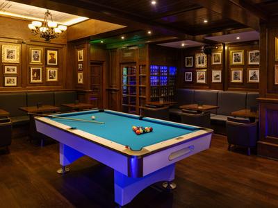 Cozy billiard room with blue table, comfortable seating, and warm wooden decor.