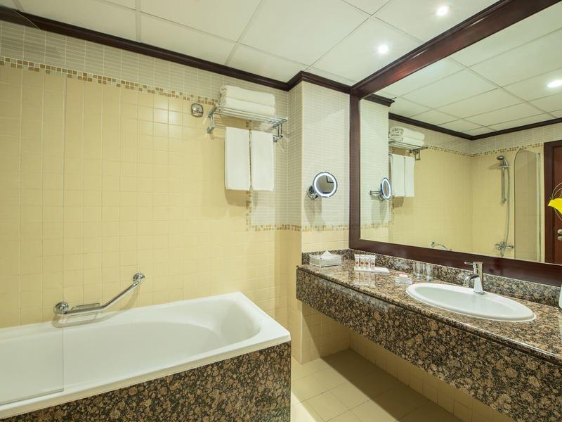 Nowoczesna łazienka z wanną, dużym lustrem i podwójną umywalką z granitowym blatem.